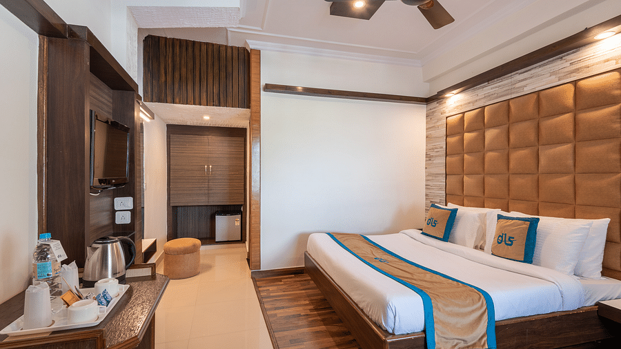 A welcoming hotel room with a comfortable bed, a TV, a mini-fridge, and a balcony offering a view - DLS Meghavan Resort